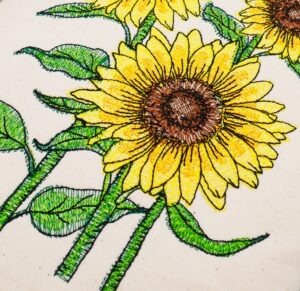Gestickte Sonnenblumen auf Baumwollstoff als kreative Betätigungsaktivität in der Ergotherapie bei Depressionen
